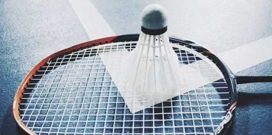 Federball auf Badminton-Schl&auml;ger, der auf dem Spielfeld liegt 