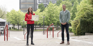 Athletin Verena Meisel und Hochschulsportleiter Christoph Edeler präsentieren die FISU-Scheibe