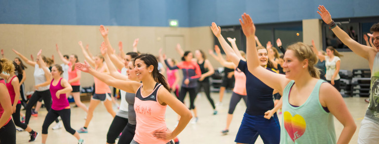 Teilnehmende eines Fitnesskurses machen eine Übung