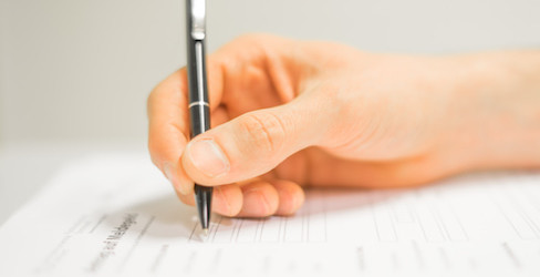Hand mit Stift beim Formular ausfüllen 