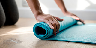 Frau rollt Yogamatte zusammen 