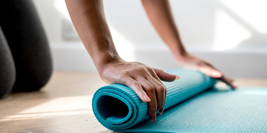 Frau rollt Yogamatte zusammen 