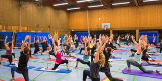 Eindruck eines HSP-Kurses, viele Teilnehmende knien jeweils auf einer Yogamatte und machen eine Übung