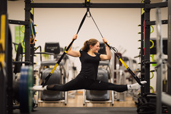 Frau macht Spagat mit Füßen im TRX-Schlingentrainer